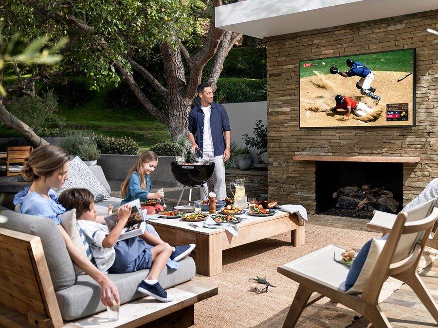 A family outside on a patio watching a Samsung outdoor TV.