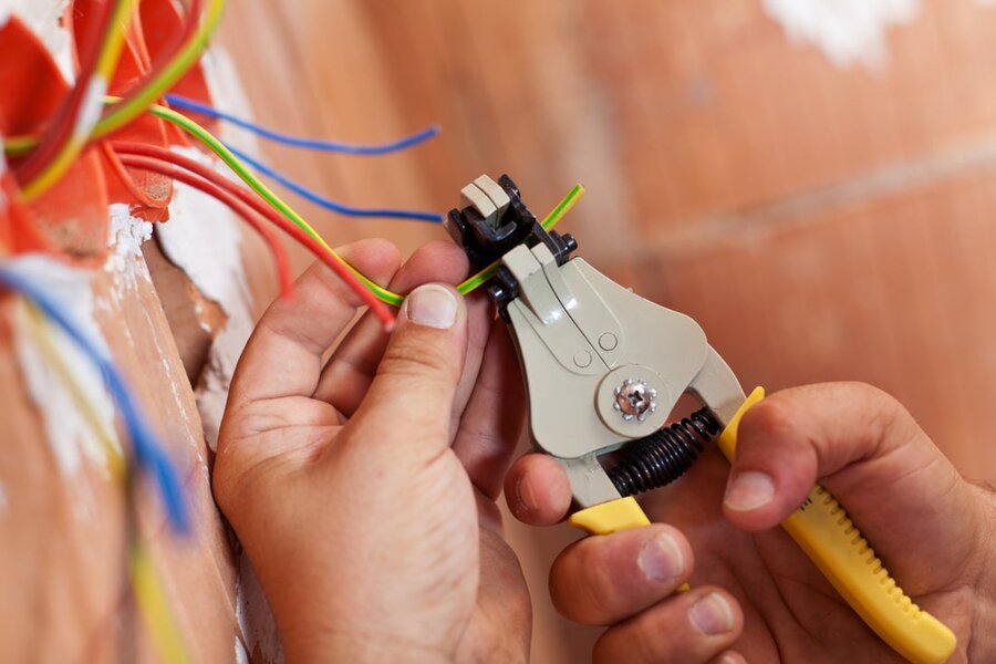 A hand in view with wire cutters working on a set of wires.